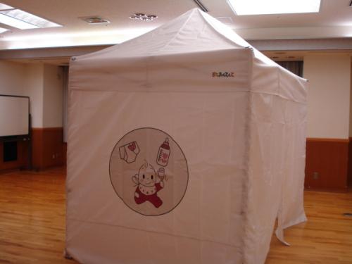 白いテントに赤ちゃんと哺乳瓶・オムツが描かれた移動式赤ちゃんの駅外観写真