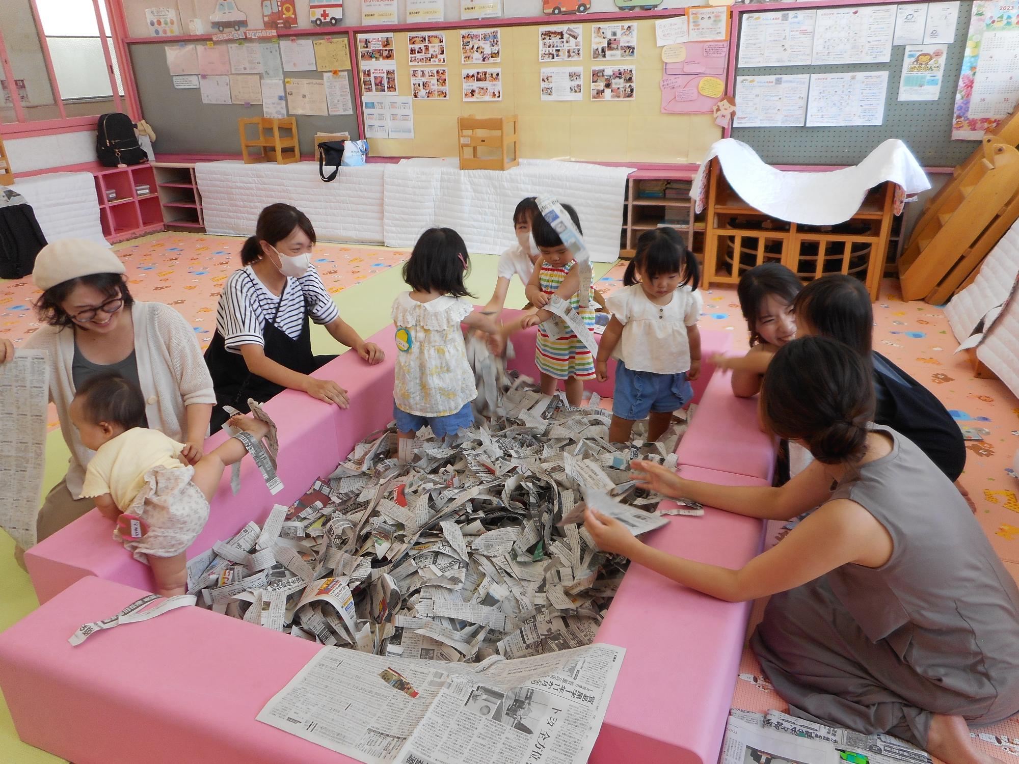 親子で新聞紙遊びをしている様子