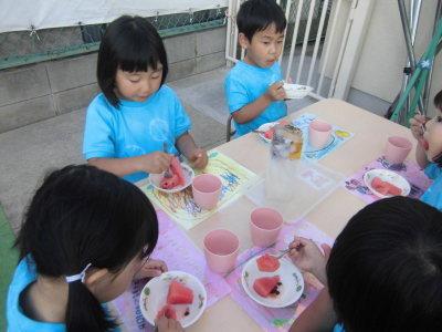 デザートのスイカをおいしそうに食べている子供たちの写真