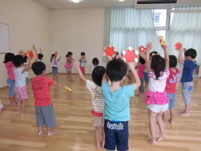 円を描くように丸くなってタンバリンを鳴らしながら踊っている子供たちの写真