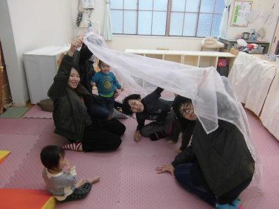 白い大きな布を使い子供達を触れ合っている参加者の人達の写真