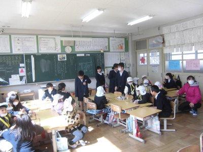 教室の中の各机に座り小学生の子供達の話を聞いている園児たちの写真