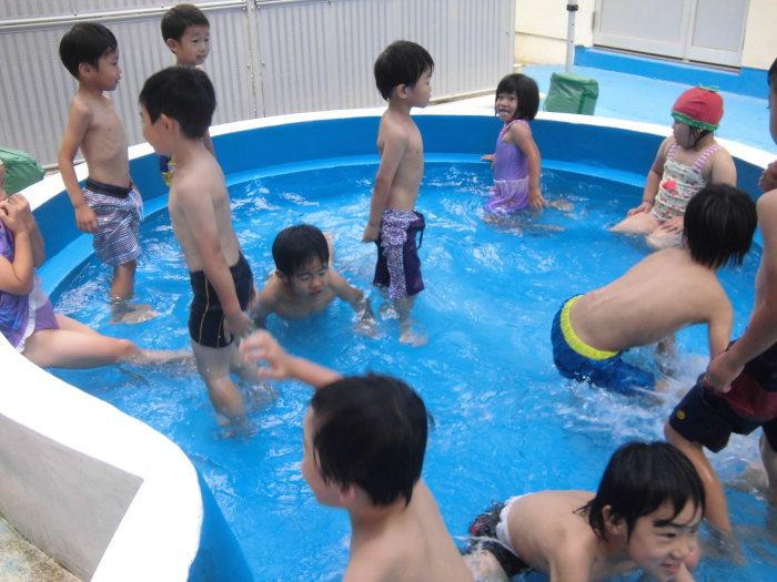 大きなプールで水遊びを楽しんでいる園児達の写真