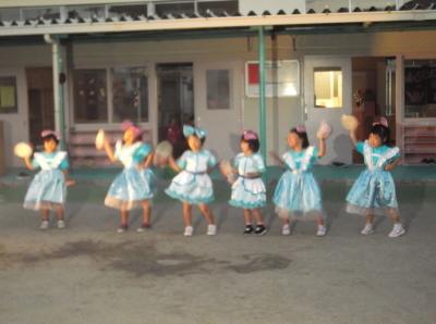 フリルのついたかわいらしい衣装を着てタンバリンを振りながらダンスをしている6人の女の子の写真