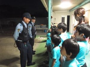 夜、園舎の軒下で2人の警察官と話をしている子供たちの写真