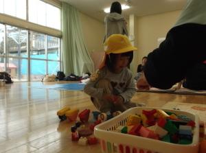 カゴいっぱいに入ったブロックで遊んでいる子供の写真