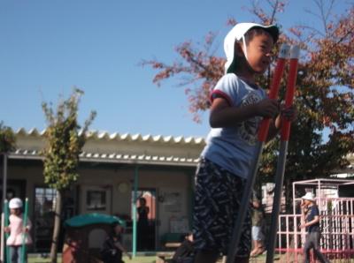 竹馬に乗って園庭を歩いている男の子の写真