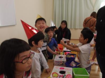 赤や黄色のとんがり帽子をかぶった子供たちとくじを引いている男の子の写真