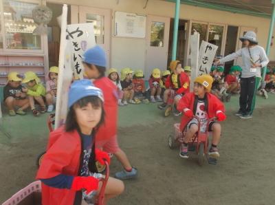 赤い法被を着て三輪車に乗っている子供たちや軒下に腰かけてやきいもを食べている子供たちの写真