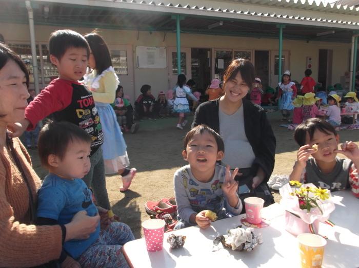 笑顔でやきいもを食べている親子連れの写真