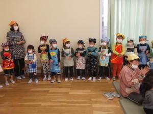 三角巾とエプロンをつけて横一列に並び歌を歌っている子供たちの写真