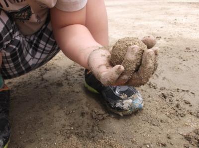 砂まみれの手で丸めた泥団子を持っている写真