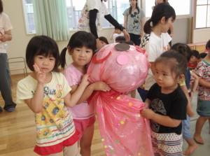 ピンク色の大きなテルテル坊主と3人の女の子の写真