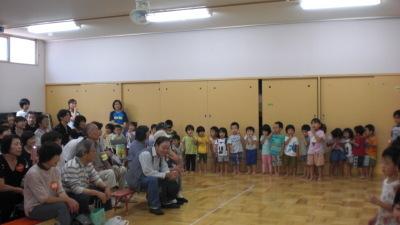 椅子に座っている祖父母と壁際に横一列に並んで立っている子ども達の写真