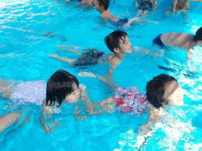 子ども達が水の中から顔だけ出して、ワニさん泳ぎをしている写真