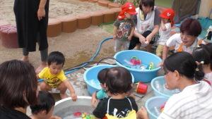 水とおもちゃの入ったタライで水遊びをする子供たちの写真
