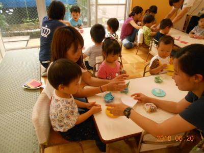 並べられた机に親子が隣り合わせで座り、体験保育製作をしている写真