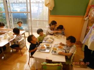 給食を食べている園児達と1人のお母さんの写真