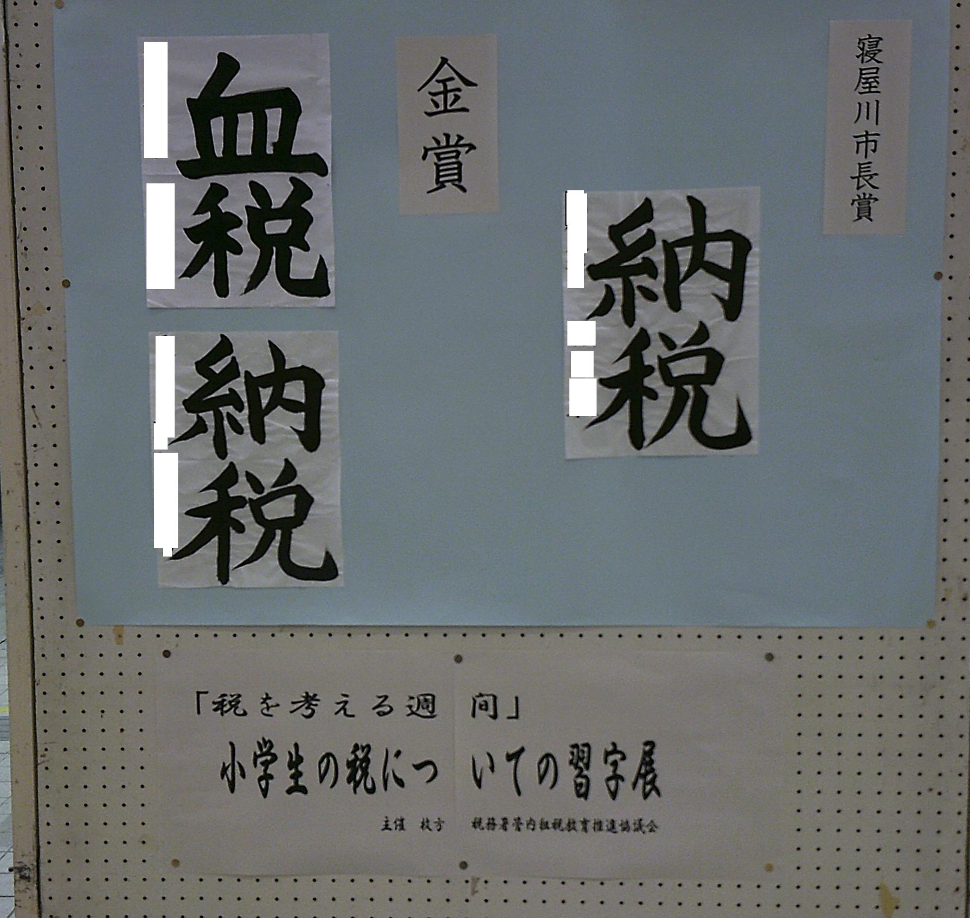 「税を考える習慣」小学生の税についての習字展を書かれた貼り紙の左側に、水色の模造紙が貼られていて寝屋川市長賞と金賞を受賞した「納税」を書かれた習字の作品が展示されている写真