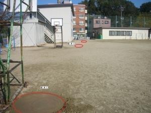 バスケットのゴールなどがあるグラウンドに給水口の位置を赤い丸で囲っている写真