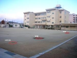 石津小学校のグラウンドに給水口のマンホールが三つ設置され、それらが赤い丸で囲われている写真