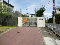 道路沿いにある施設のシルバーのゲートが閉まっており、左側にオレンジ色の看板がついている写真