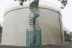らせん状の階段が設置された、白い外壁で丸い建物のタンクの写真